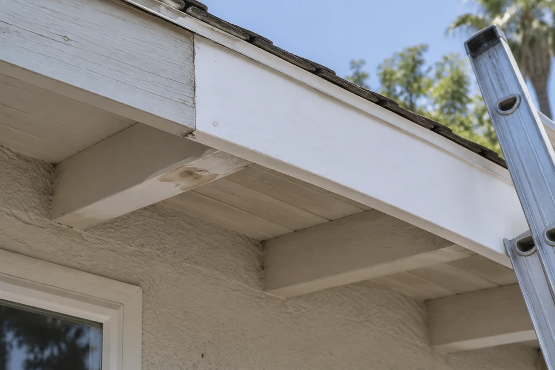 New primed fascia board spliced into old painted fascia during wood repair before exterior painting