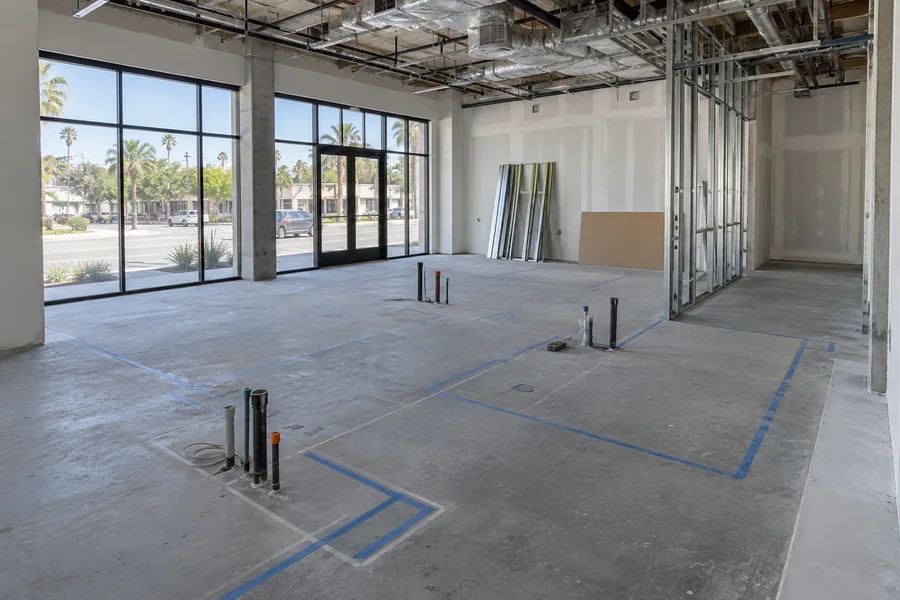 Empty commercial suite being laid out for a dental office, with chalk lines marking operatories on the slab