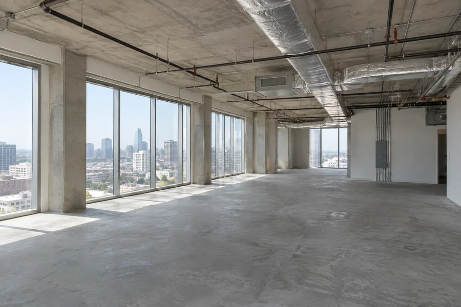 Bare shell office space with an open concrete deck and stubbed-in services, before any build-out