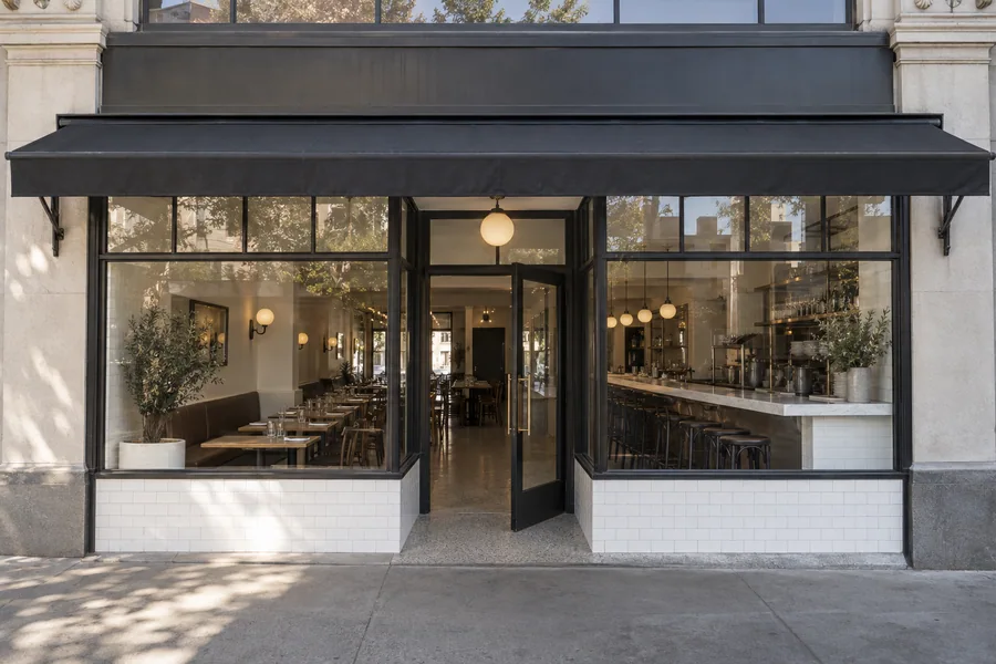 Restaurant storefront with a restored transom, black framed glass and a white tile bulkhead